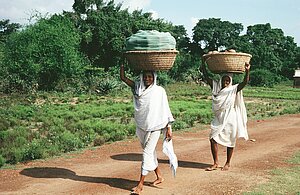 Two senior women from potter households carry pots to the temple. Tikarapada, 1980.