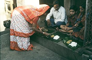 Sureswari Mishra serves mahaprasada to her husband Purna Chandra Mishra, their son Bapi, and her sister Kuni, in the courtyard of their home. Puri, 1980.